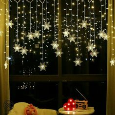 snowflakes hanging from the ceiling in front of a window with lights on it