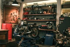 two motorcycles are parked next to each other in a room filled with shelves and tools