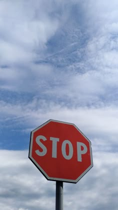 a red stop sign sitting under a cloudy blue sky