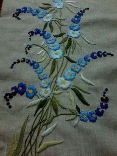 blue flowers are embroidered onto the side of a piece of cloth with green stems and yellow centers