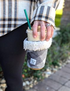 a person is holding a cup with a straw in it while wearing leggings