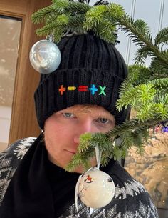 a man wearing a black hat and holding a christmas ornament