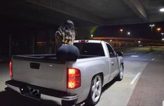 a woman sitting on the back of a truck in a parking lot at night time