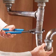 two people are fixing a sink faucet with blue plastic handles and wrenches