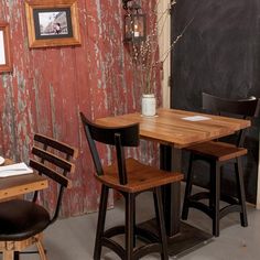 three wooden chairs sitting at a table in front of a chalkboard