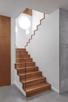 there is a wooden stair case in the room that has white walls and wood steps