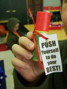 a young boy holding up a bottle with a sign on it that says push yourself to do your best