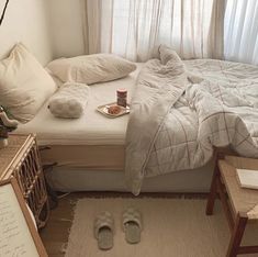 an unmade bed in a bedroom with white linens and pillows on the floor