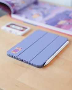 a tablet sitting on top of a wooden table next to a cell phone and book