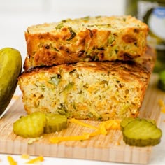 two slices of zucchini bread sitting on top of a cutting board next to a pickle