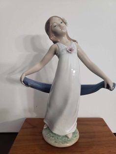 a ceramic figurine holding a blue object on top of a wooden table