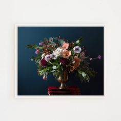 a vase filled with lots of flowers sitting on top of a red table next to a blue wall