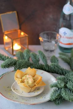 a white plate topped with food next to a bottle of water and pine branches on top of a table