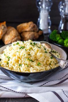 a bowl filled with rice next to broccoli and other food on a table