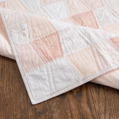 two quilts laying on top of each other on a wooden floor with wood floors