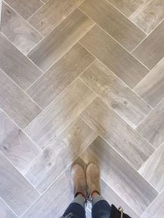 a person standing on top of a wooden floor next to a white tile flooring