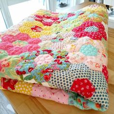 a quilt is laying on top of a wooden table next to a window with an open door