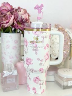 a pink and white coffee cup sitting on top of a table next to some flowers