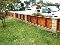 a white truck parked next to a wooden planter in the grass near a fence