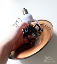 a hand holding an electric light bulb over a plate with scissors and wire on it