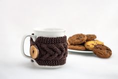 there is a coffee cup and some cookies on the plate next to it, both made out of knitted yarn