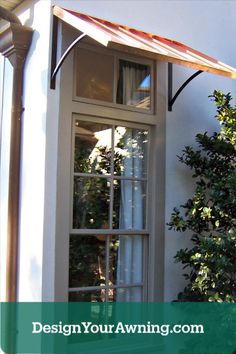 an open window on the side of a white building with trees in front of it