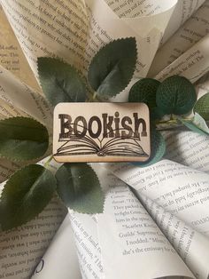 a bookish magnet sitting on top of an open book next to some green leaves