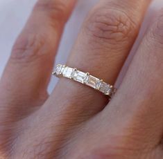 a woman's hand with a diamond ring on top of her finger and the band is