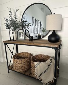 a table with two baskets and a mirror on top of it next to a lamp