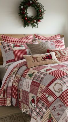 a christmas themed bed in a bedroom with red and white plaid comforter, wreath on the wall