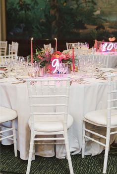 the table is set up with white chairs and pink centerpieces