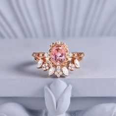 a pink diamond ring sitting on top of a white surface