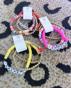 four bracelets with name tags on them sitting on the floor next to a carpet