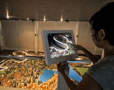 a woman is looking at a model of a city on a computer screen in front of her