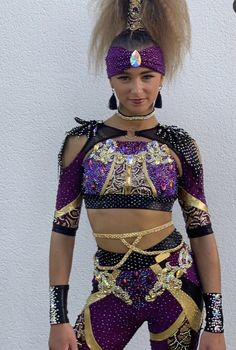 a woman in a purple and gold belly dance outfit, with her hair pulled back