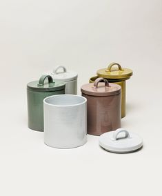 four different colored containers with lids on them