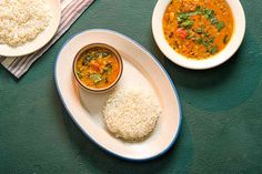 two plates with rice and curry next to each other on a green tablecloth,