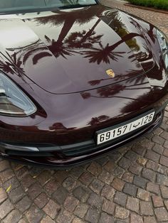 a maroon sports car is parked on the side of the road with palm trees in the background