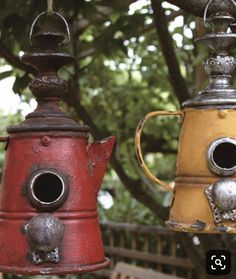 two metal tea kettles hanging from a tree