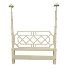 a white headboard with two posts and an iron bar on the bottom one side