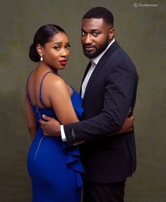 a man and woman in formal wear posing for a photo with their arms around each other