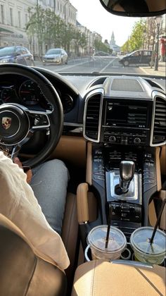 the interior of a car with steering wheel and cup holders in front of it, as seen from behind