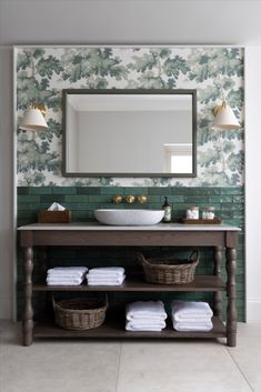 a bathroom with green wallpaper and white towels on the shelf, under a large mirror