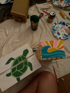 a person sitting on the ground with some art supplies and paper plates in front of them