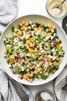 a white bowl filled with broccoli, chickpeas and other food items