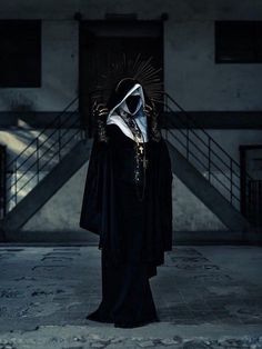 a person wearing a nun costume standing in front of stairs