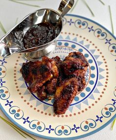 two pieces of meat sitting on top of a blue and white plate next to a spoon