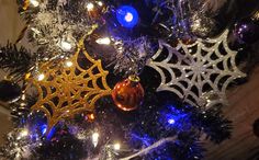 a decorated christmas tree with spider webs and balls on it's branches in blue, silver and gold lights