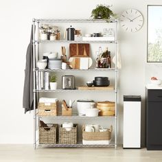 a kitchen with white walls and shelves filled with dishes, pans and utensils