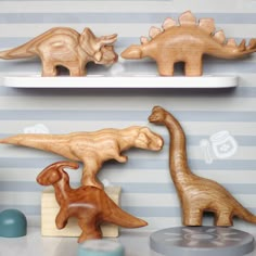 three wooden dinosaurs are sitting on shelves